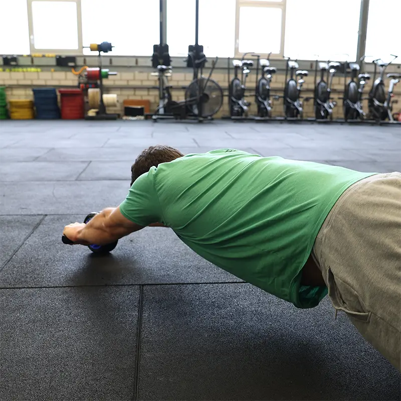 Mann trainiert mit Ab Roller im Gym – Bauchmuskelübung in gestreckter Position