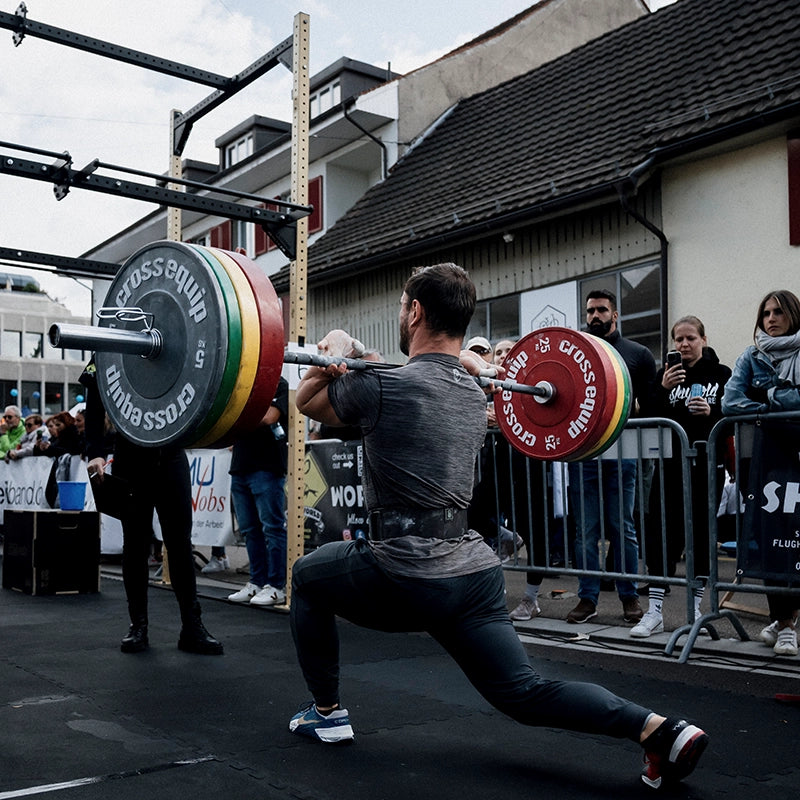 Man hebt viele Gewichte draußen auf aufgebautem Sportgelände