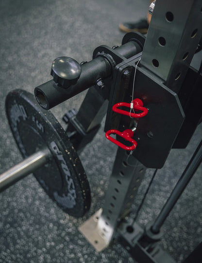Detail des Leg Extension & Curl Attachment – Hantelaufnahme mit Lochscheibe, Drehknopf und rote Zugringe der Steckbolzen an der Montageplatte