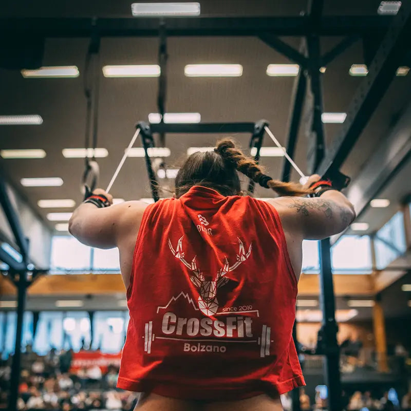 Athletin an Turnringen beim CrossFit Wettkampf – Rückenansicht mit rotem CrossFit Bolzano Shirt