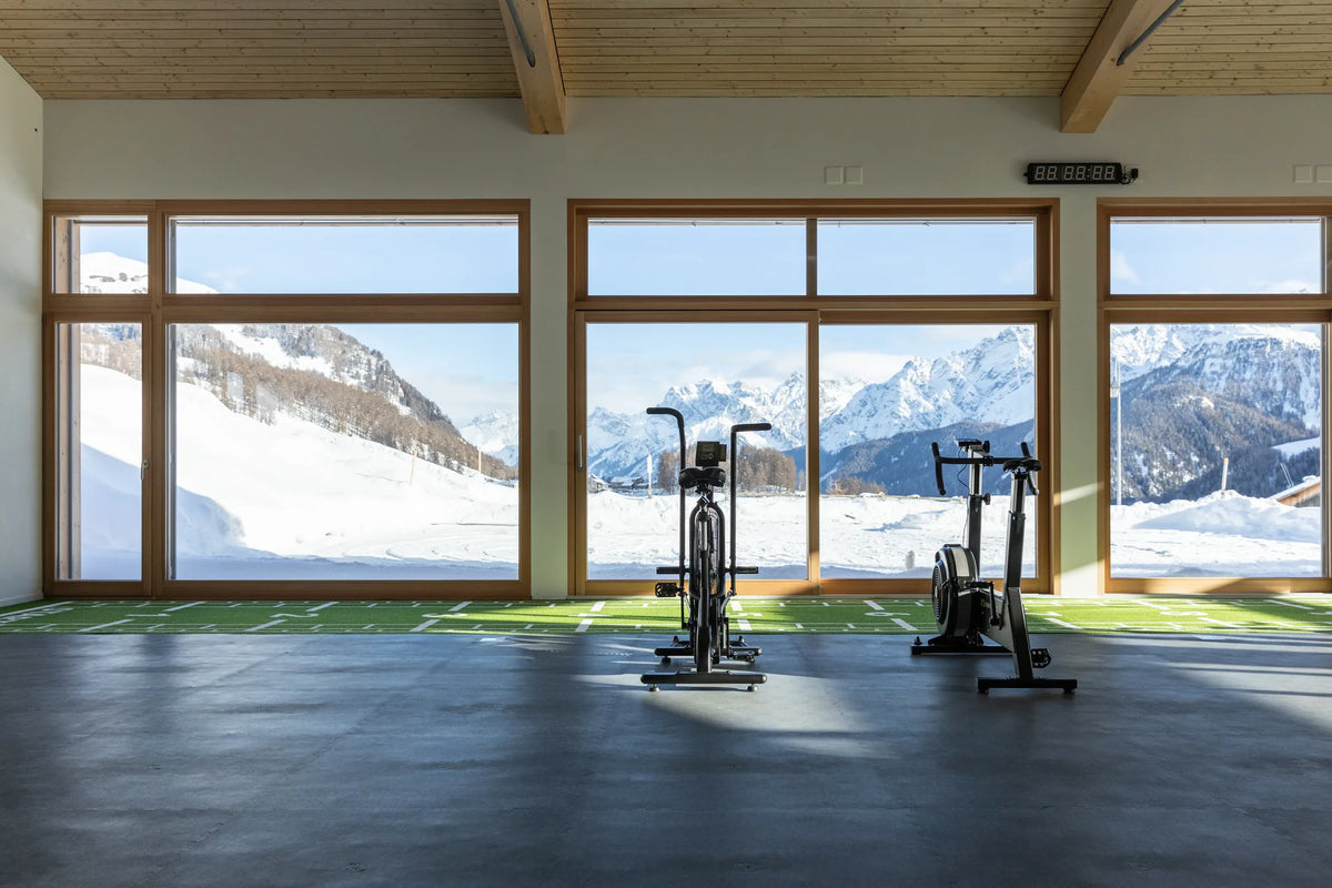Cardio-Bikes im Gym des Meisser Resort in Guarda mit Blick auf die verschneite Engadiner Bergwelt