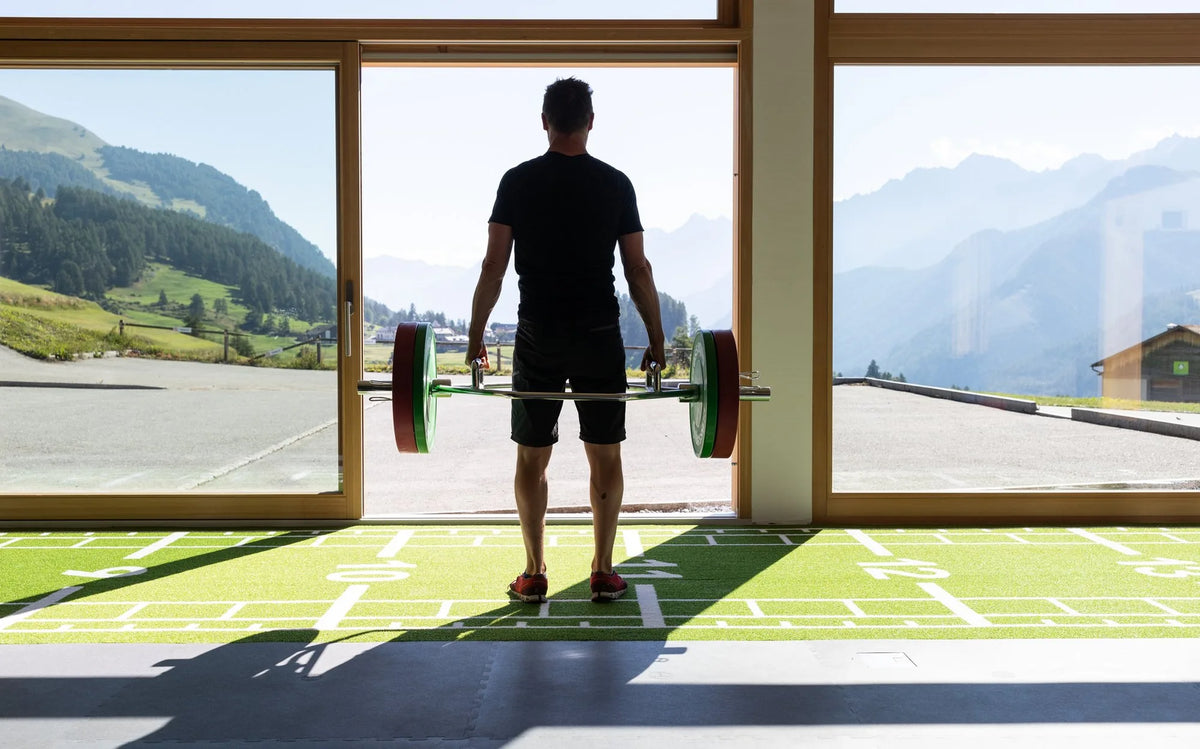 Athlet trainiert mit Trap Bar vor Engadiner Bergpanorama im Gym des Meisser Resort in Guarda