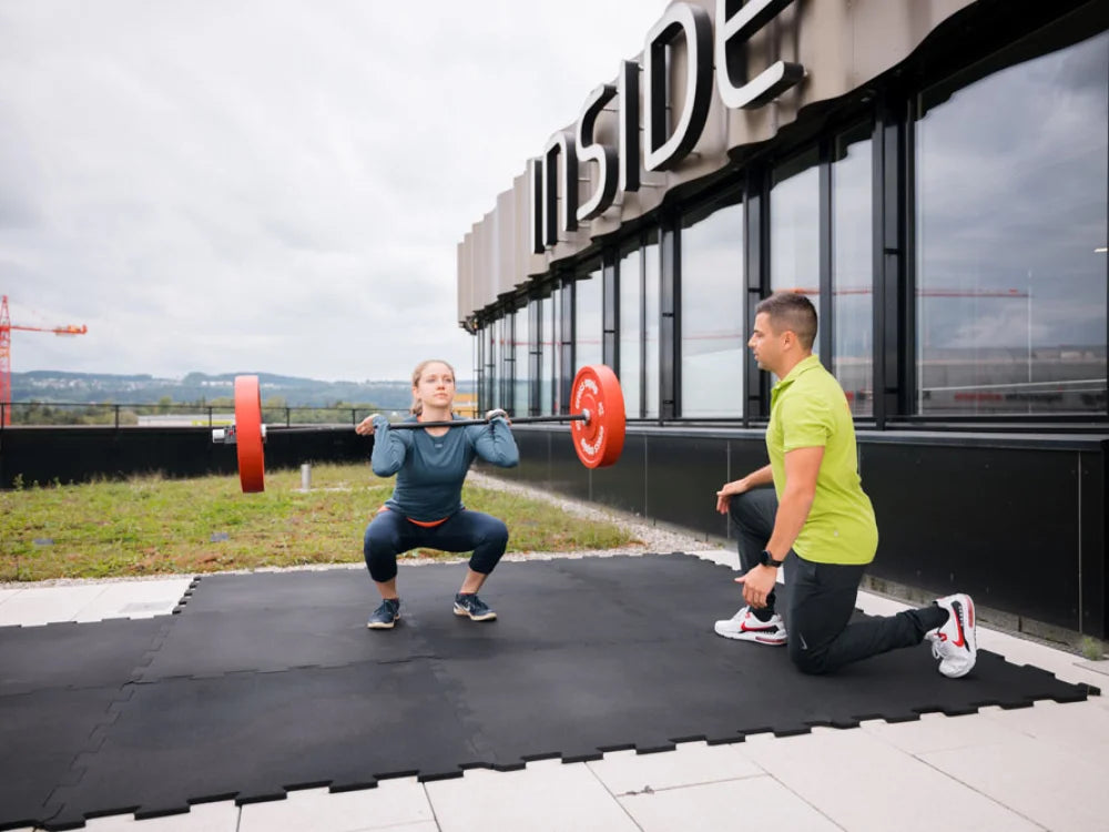 Physiotherapeut betreut einen Front Squat im Athletiktraining vor der PhysioBase in Volketswil