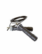 Premium Jump Rope – zwei Griffe mit anthrazitfarbenem, perforiertem Griffband umwickelt, dahinter das aufgerollte dunkle Stahlseil