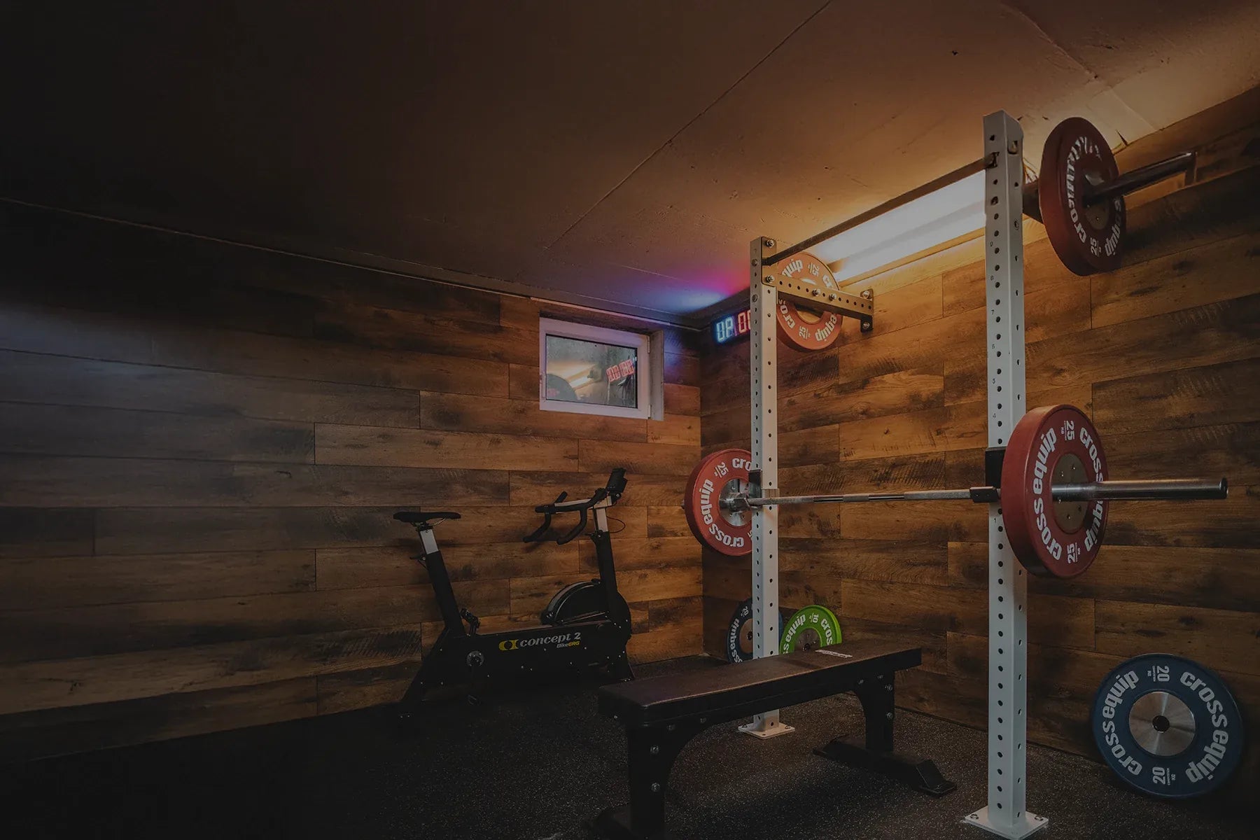 Homegym von cross equip mit Squat Rack, Bumper Plates, Bike-ERG und Bench – kompaktes Setup im Kellerraum