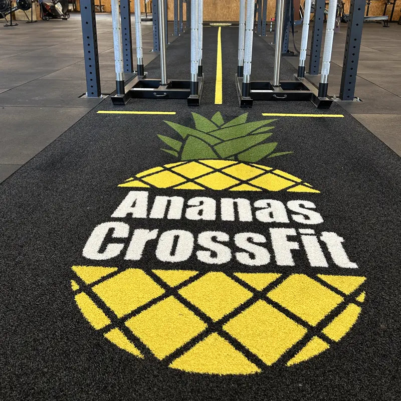 Performance Turf nach Mass bei Ananas CrossFit — schwarze Sprintbahn mit eingewebtem Vereinslogo und gelber Mittellinie zwischen zwei Racks